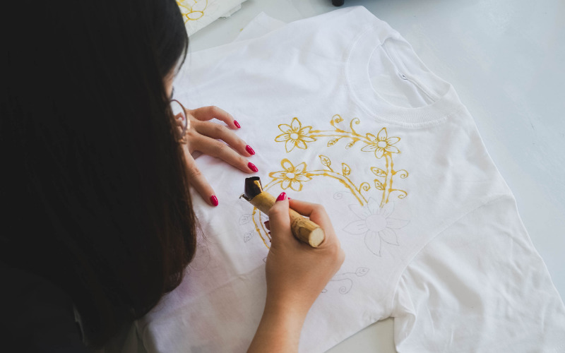 Tracing a batik pattern with hot wax using a traditional canting tool